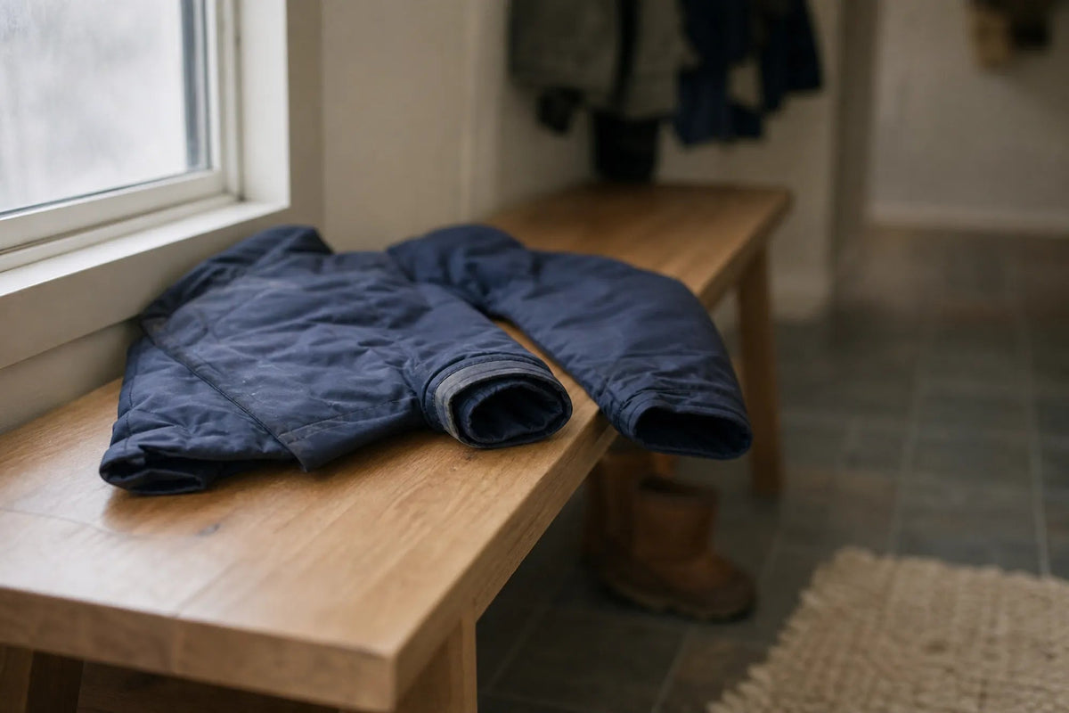 A child's winter jacket on a wooden bench, one sleeve cuff turned back to show the extra fabric folded inside it.