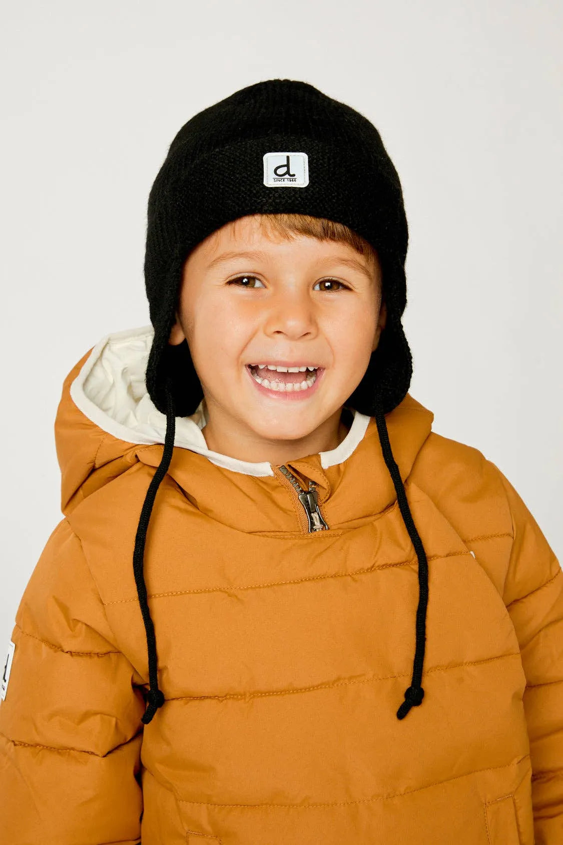 Child wearing the Black knit winter hat with its ear flaps and ties visible