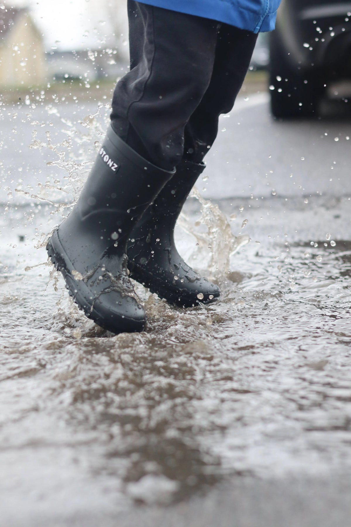 Child splashing in Black/Black Stonz rain boots