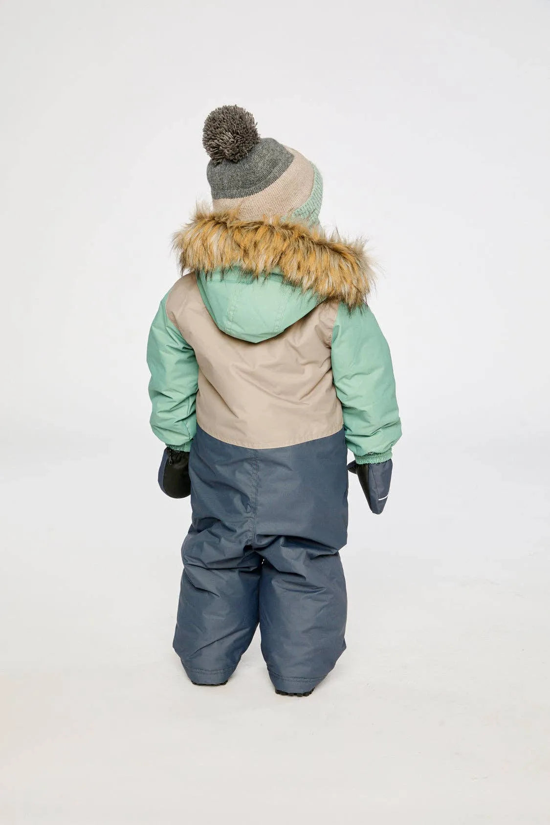 Child wearing the one-piece snowsuit, back view showing the hood and colour blocking