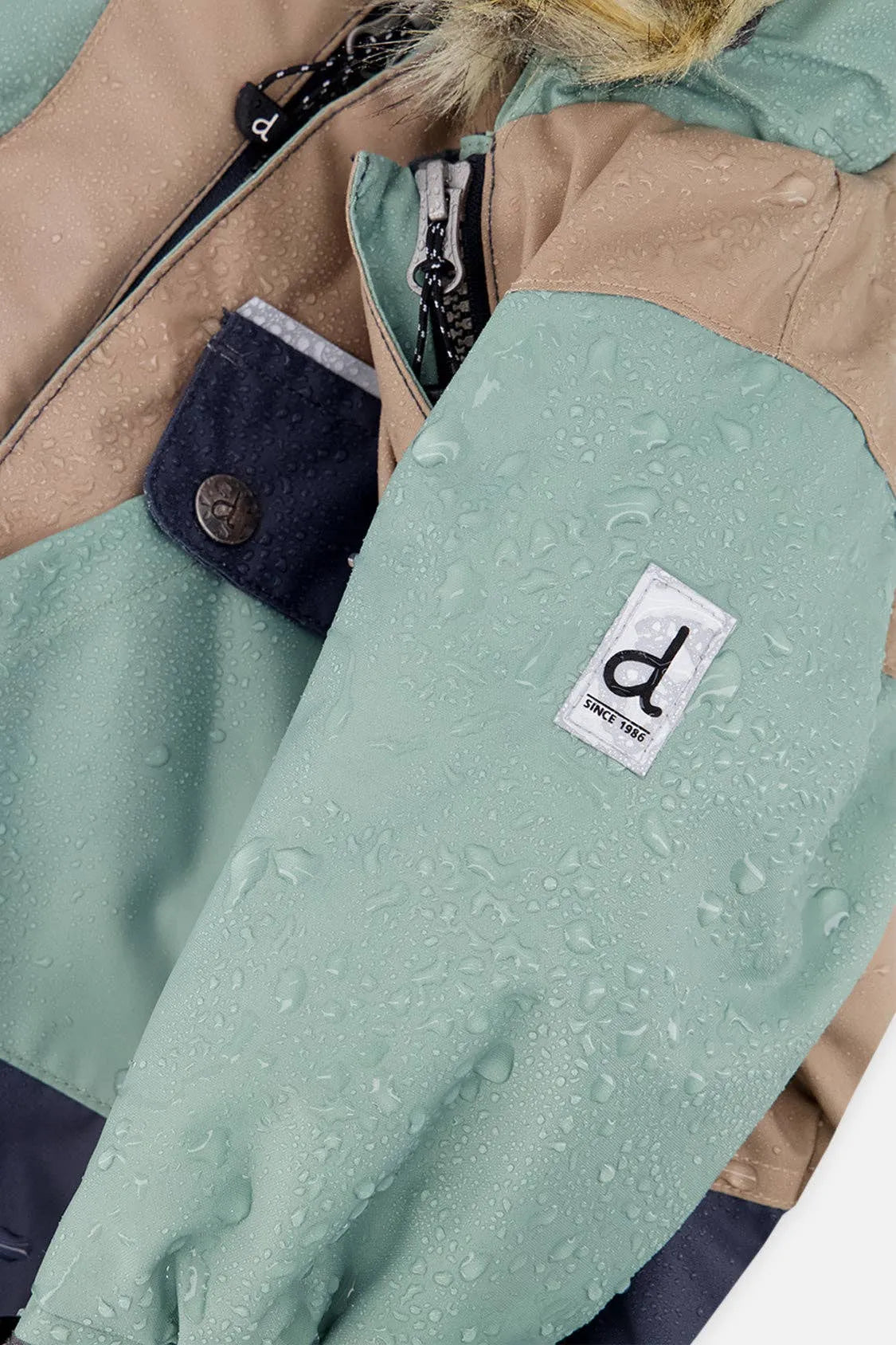Close view of water beading on the mint and taupe snowsuit shell